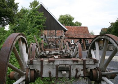 Die Stellmacherei von außen. Vor dem Gebäude stehen alte Wagenräder