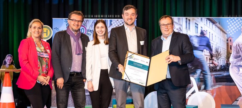 Das Bild zeigt die Urkundenübergabe zur Mitgliedschaft Warendorfs zum Zukunftsnetz Mobilität NRW. Auf dem Foto sind von rechts nach links: NRW-Verkehrsminister Oliver Krischer, Bürgermeister Peter Horstmann, Mobilitätsmanagerin Lea Licher, NWL-Geschäftsführer Joachim Künzel und Daniela Niestroy-Althaus vom Zukunftsnetz Mobilität NRW.