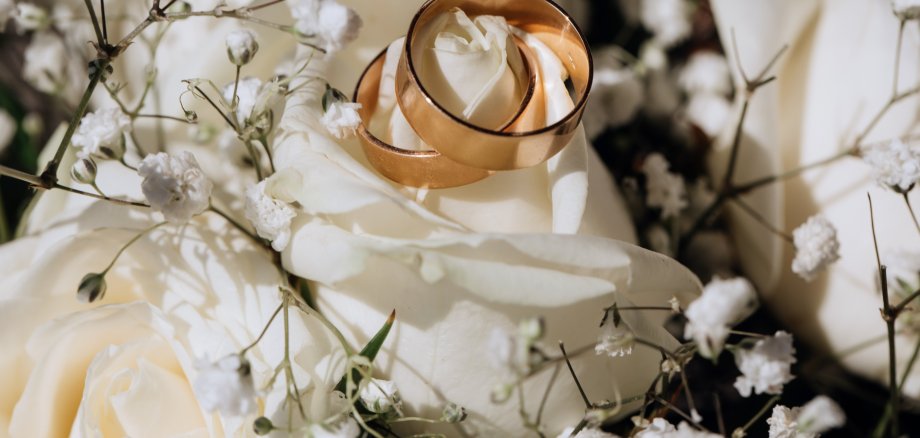 Golden wedding rings on the white rose  from the wedding bouquet